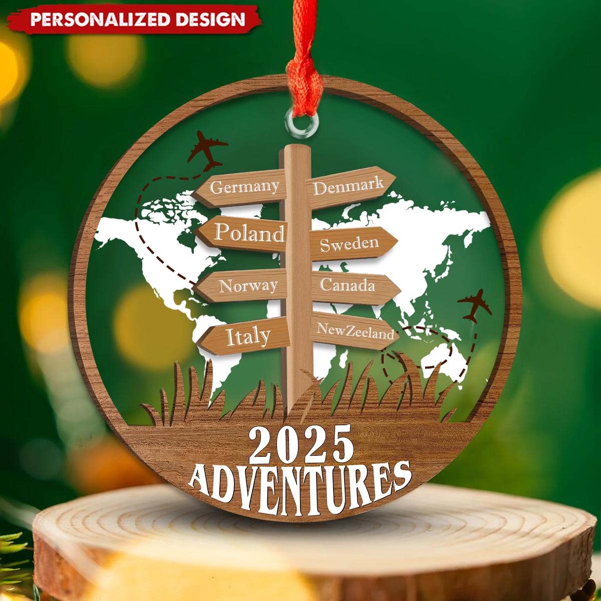 The travel ornament with a red ribbon in front of warm festive lights